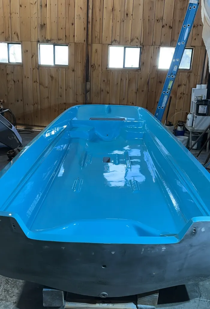 Freshly laid blue fiberglass hull inside the barn